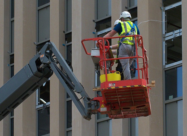 Worker in a man lift basket at a building