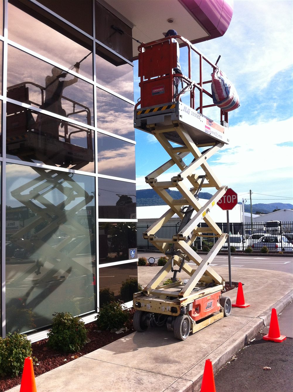 Worker on a scissor lift cleaning a storefront